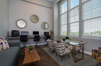 A living room with a grey couch, a glass table, and a wall with three round mirrors.